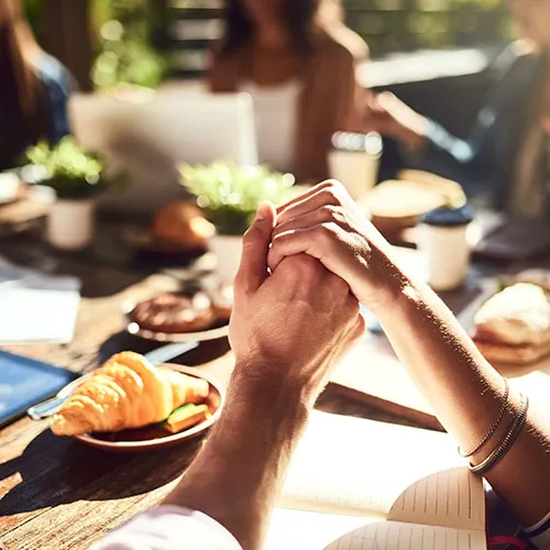 two hands holding around a table of food